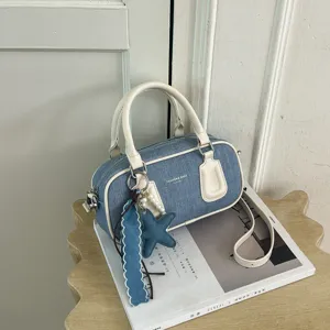 Denim Boston handbag detail view, white leather trim and cute star charm for daily wear.