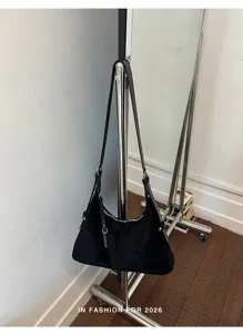 Detailopname van een stijlvolle zwarte schoudertas hangend aan een rek voor dagelijks gebruik.