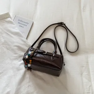 Detail view of a chic brown leather bowling pillow handbag featuring a cute beaded charm.