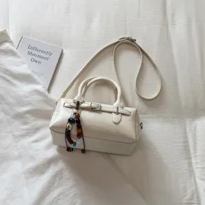 Detailed shot of a stylish white bowling handbag with beaded charm, showcasing fine texture.