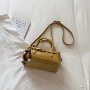 Yellow bowling pillow handbag detailed view, PU leather crossbody bag with beaded charm and strap.