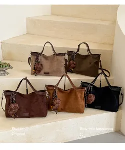 Detailansicht lässiger, weicher Wildleder-Shopper in verschiedenen Farben mit Karomotiv-Anhänger.