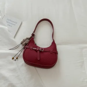 Detalle de bolso de hombro medialuna burdeos, elegante bolso hobo de piel PU con borla.