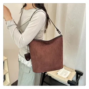 Vista dettagliata di una borsa a tracolla minimalista in camoscio marrone in stile chic.