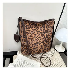 Dettaglio borsa a tracolla in camoscio leopardato con finiture in pelle marrone scuro.
