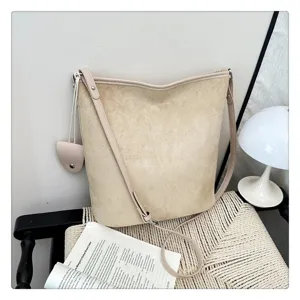 Dettaglio della borsa a secchiello retrò minimalista in morbido camoscio con tracolla.
