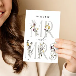 Close-up detail of a minimalist wedding greeting card featuring floral typography and elegant design.