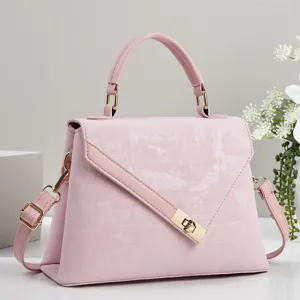 Détail de sac à bandoulière rose élégant, quincaillerie dorée chic et serrure en métal.