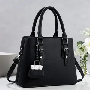 Vista detallada del bolso de mujer en cuero sintético negro con asas dobles y mini colgante.