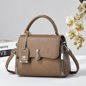 Brown leather top-handle crossbody bag detail, featuring metal zipper and elegant texture.
