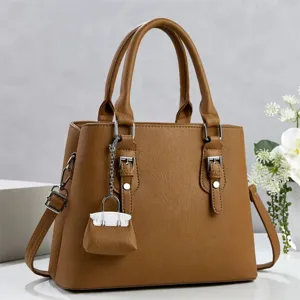 Vista detallada de bolso de mano marrón para mujer de cuero sintético con dije de cerradura.