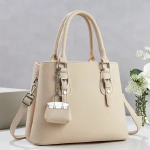 Detalle de bolso de cuero beige con textura fina, hebilla de metal y mini candado.