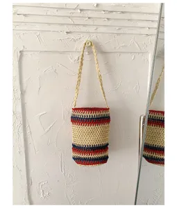 Detailansicht der Retro geflochtenen Eimer Tasche mit rot-blauen Streifen und feiner Stroh Textur.