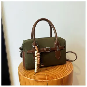 Close-up detail of the retro green pillow handbag, featuring chic wooden bead charm and belt.