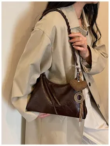 Sac à épaule bandoulière marron foncé élégant en cuir avec lanière tressée et charm.