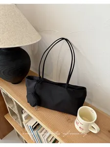 Minimalist black nylon shoulder tote bag with small pouch for women daily casual commuting.