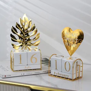 Luxury metal leaf and heart perpetual calendar ornament with golden stand and white date cubes.