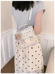 Detail shot of a trendy Korean style women backpack with cute bear pendant and bow knot.