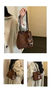 Brown suede bucket bag detail showcasing vintage style, double straps and cute flower pendant.