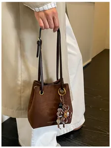 Retro suede bucket bag for women, stylish brown shoulder handbag with floral charm detail.