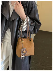 Vintage brown suede bucket bag for women, chic shoulder bag with flower charm and slim strap.