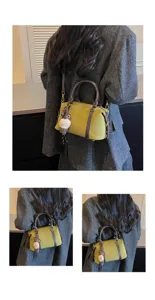 Detailed view of retro green suede Boston bag with brown leather trim worn over shoulder.