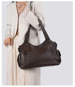 Detail view of the dark brown leather shoulder bag featuring multiple functional zippers.