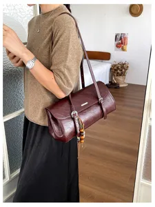 Vintage dark red cylindrical shoulder bag with delicate straps and tassels for women's daily commute.