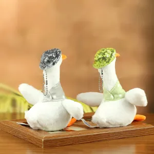Detail shot of cute plush duck toys wearing sparkly sequin hats and tiny scarves on a wooden tray.