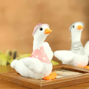 Plush duck toy detail view, cute stuffed white goose doll with pink polka dot scarf and hat.
