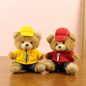 Cute plush teddy bears wearing yellow and red jackets and caps, displayed on a wooden desk.