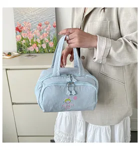 Hellblaue Kosmetiktasche Detail mit Doppelreißverschlüssen, Astronautenprint und Henkeln.