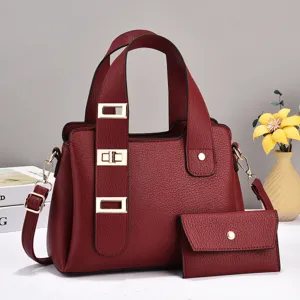 Détail d'un sac à main en cuir rouge avec serrures métalliques élégantes et pochette assortie.