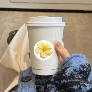 Close-up of a floral round sticker on a white paper cup, perfect for DIY journaling decor.