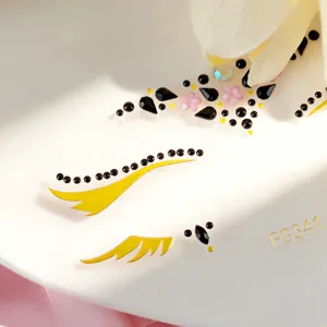 Primer plano de pedrería facial en negro y oro, cristales brillantes para maquillaje de fiesta.
