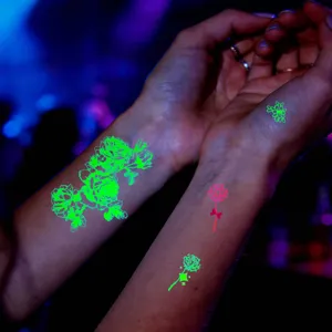 Gros plan détaillé de tatouages temporaires fluorescents roses lumineux sur les poignets.