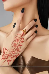 Exquisite gold triangle ring detail with red henna butterfly tattoo design on hand for women fashion.