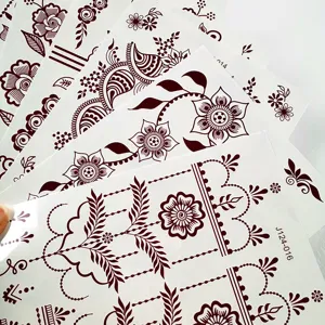 Close-up detail of brown henna temporary tattoo sheets featuring intricate floral lace patterns.