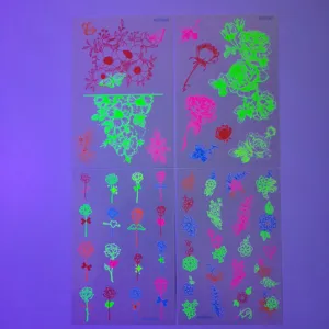 Détail de feuilles de tatouages temporaires fluorescents et lumineux avec des roses et fleurs.