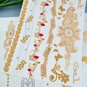 Detailed shot of metallic gold silver henna temporary tattoo sheets with floral butterfly patterns.