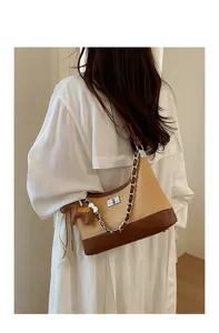 Detail shot of straw woven shoulder bag with brown leather trim and cute horse charm.