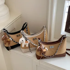Detail view of stylish straw shoulder bags featuring metallic chains and cute horse pendants.