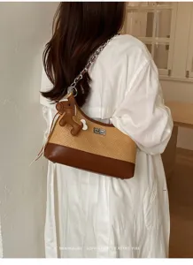 Detailed view of stylish straw shoulder bag with chain strap and cute leather horse charm.