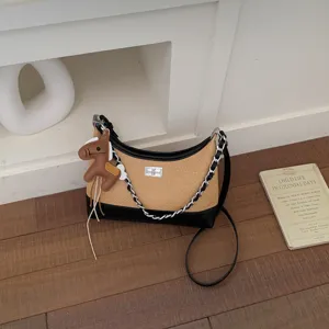 Detailed view of a retro straw hobo shoulder bag featuring black leather, chain strap, and cute horse charm.