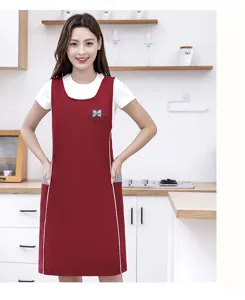 Detailed view of women sleeveless waterproof kitchen apron in red with white trim and handy pockets.