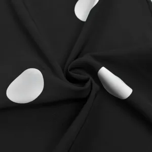 Close-up detail of black fabric with classic white polka dots, smooth texture and nice drape.