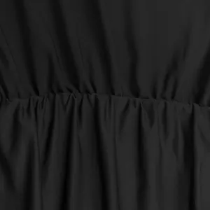 Close up detail of black women's jumpsuit fabric featuring elegant ruched design texture.