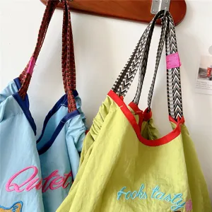 Casual embroidered tote bag with stylish contrast webbing handles and cute lettering design.