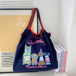 Detailed view of the dark blue canvas tote bag featuring cute embroidered dogs and artistic letters.