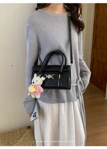 Detailansicht der schwarzen gewebten Ledertasche mit schickem Metallschloss und Plüschbär.